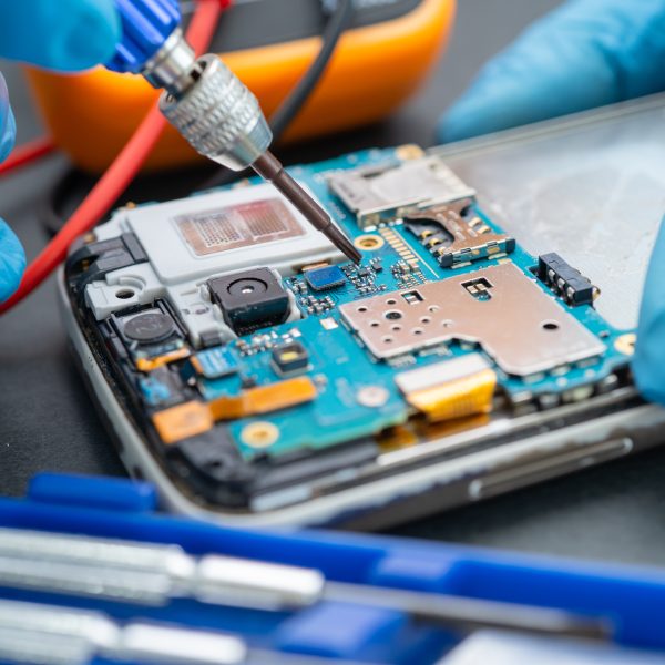 Technician repairing inside of mobile phone by soldering iron. Integrated circuit. the concept of data, hardware, technology.